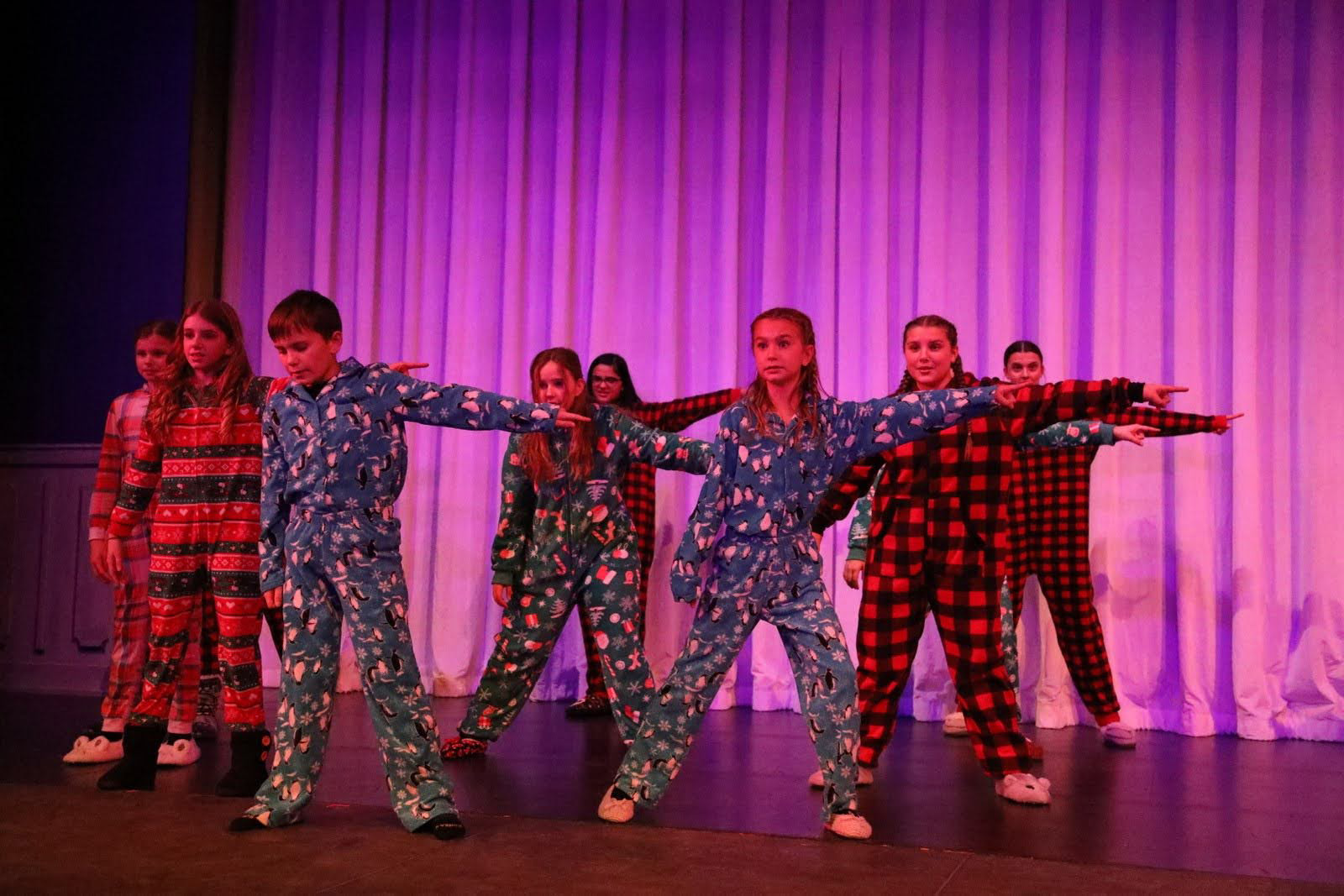 Teens dressed in fleece pajamas pose as if pointing