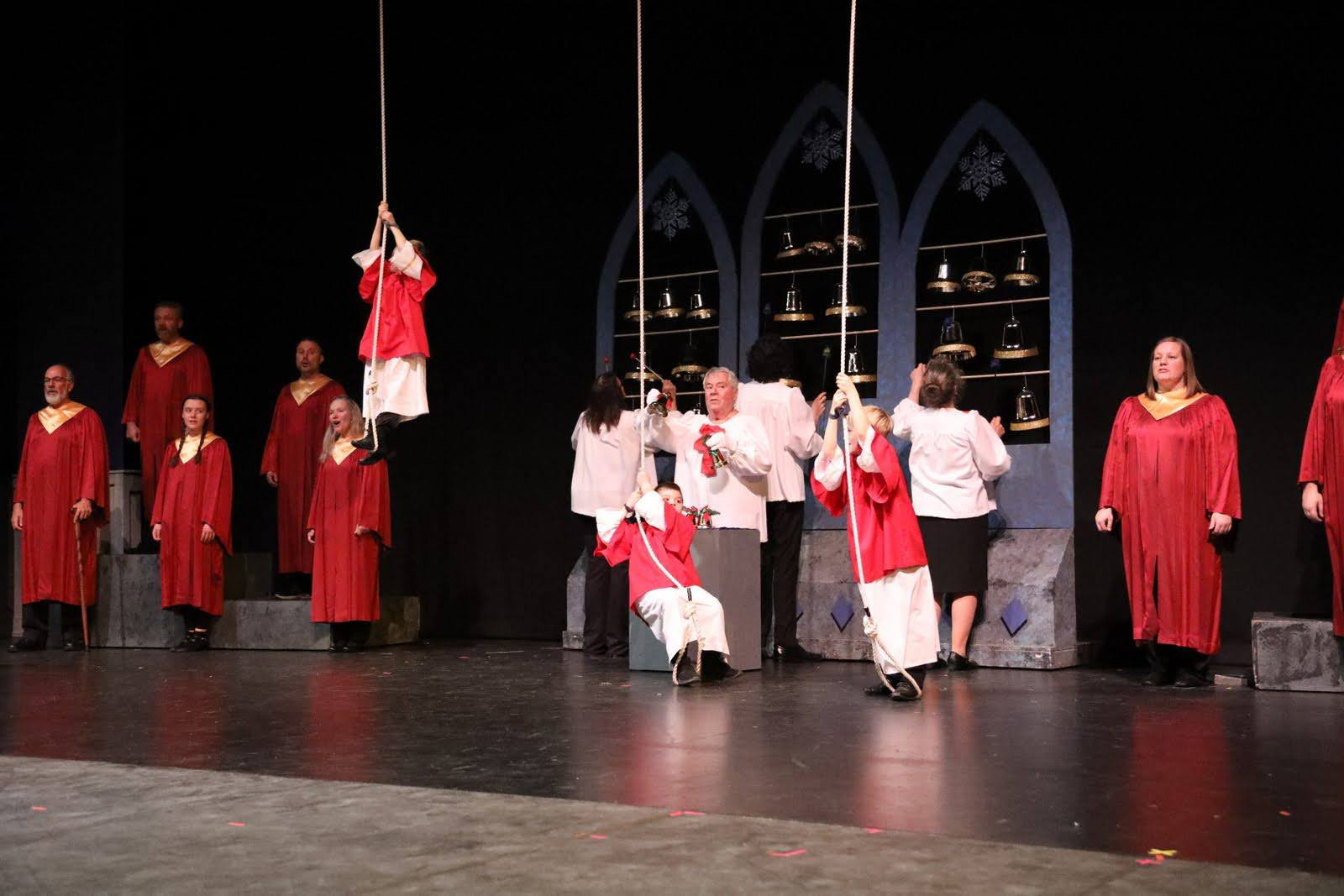 Adults sing and ring bells as young children pull bell ropes.